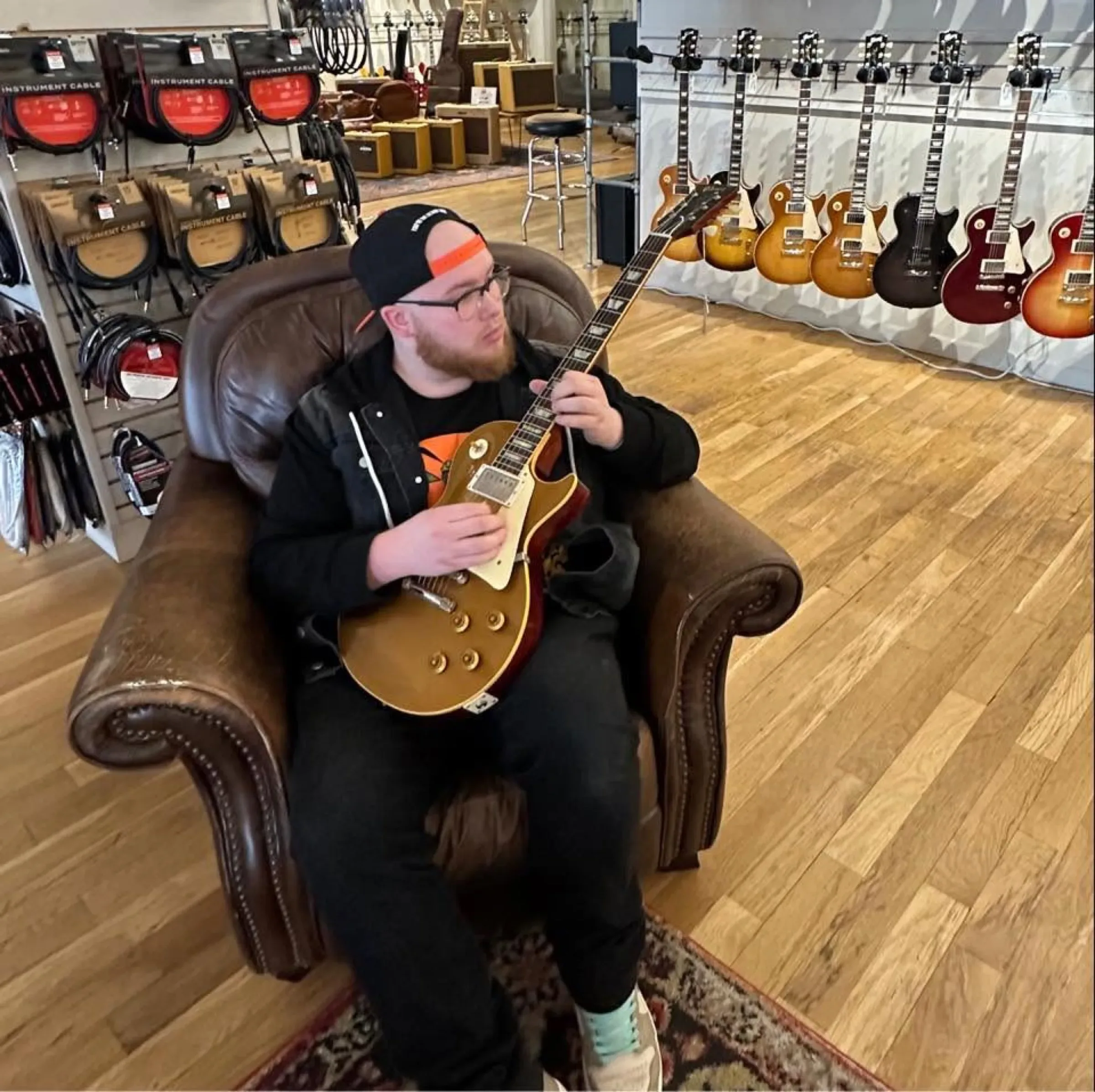Aiden with a gold-top Les Paul in a guitar shop